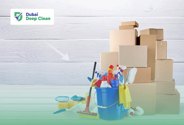 A blue cleaning bucket filled with professional detergents, spray bottles, and brushes, placed next to a stack of cardboard boxes against a white wooden wall.